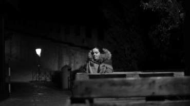 Una donna sola che pensa alla luce di un lampione seduta su una panchina.