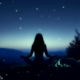 Una ragazza che fa yoga di notte su una montagna