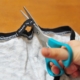 Una mano di un bambino che con una forbice toglie l'etichetta alla maglia