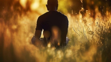 Un uomo solo che riflette in mezzo a un campo di erba
