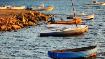 Delle barche sulla riva di una costa in Sardegna al tramonto