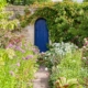 Una porta blu attraverso un giardino fiorito