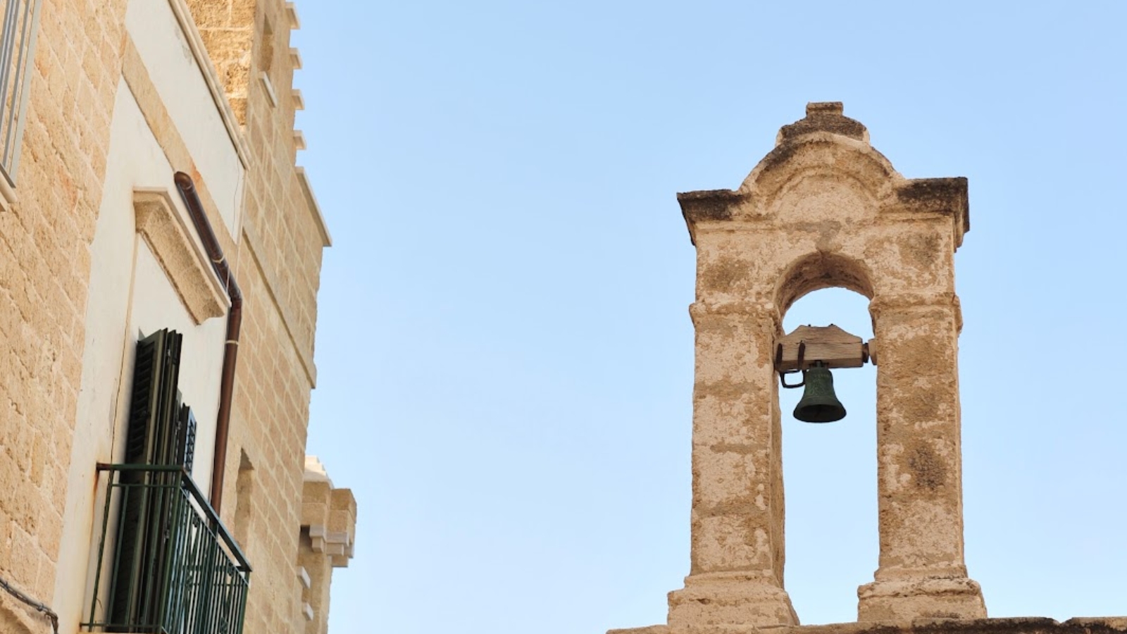 Un campanile fermo tra le case a Polignano a mare