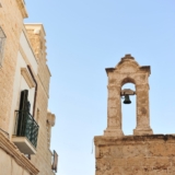 Un campanile fermo tra le case a Polignano a mare