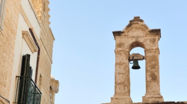 Un campanile fermo tra le case a Polignano a mare