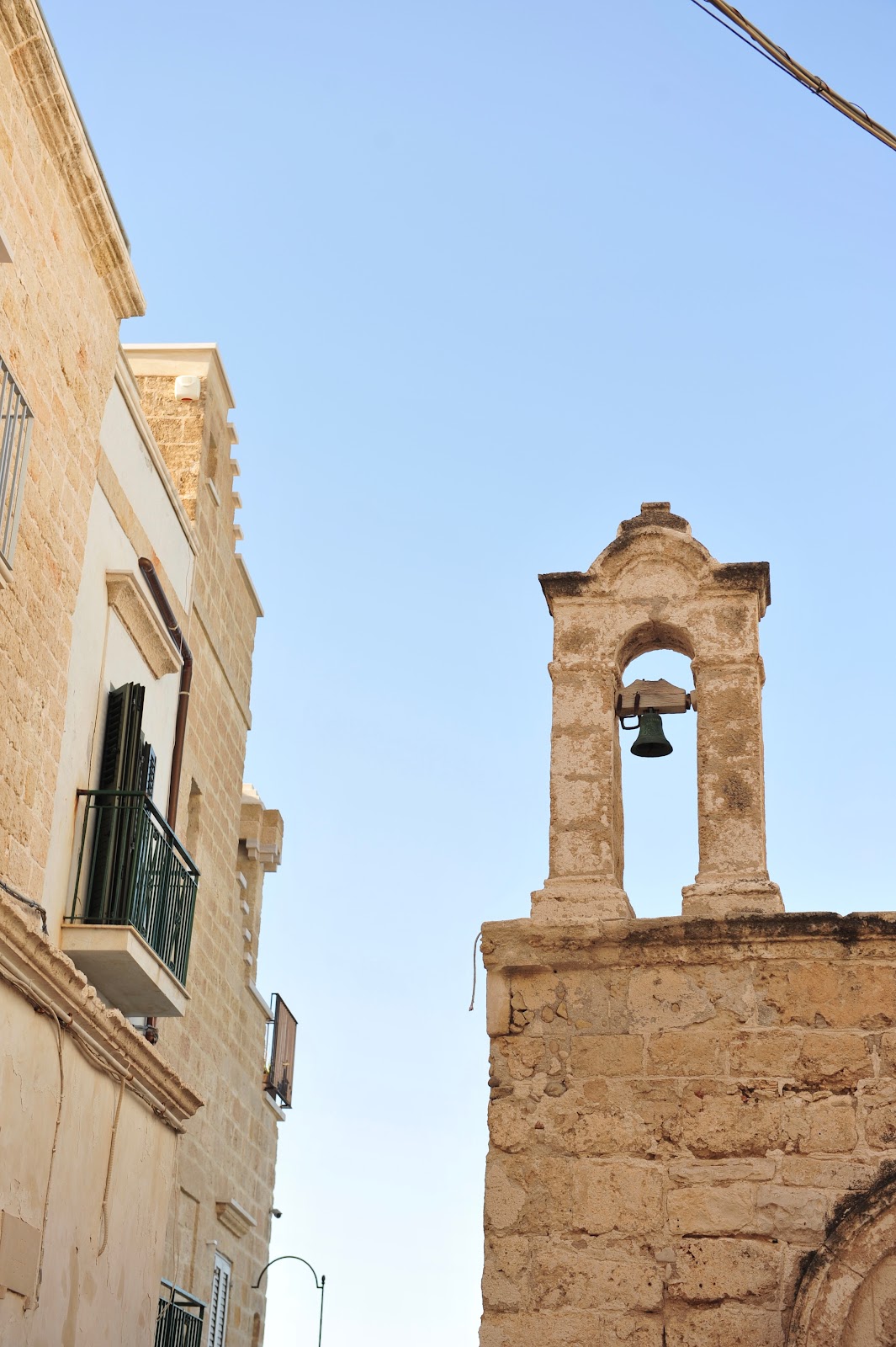 Un campanile fermo tra le case a Polignano a mare
