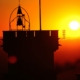 Una torre con una campana sopra, in contrasto con un splendido tramonto arancione