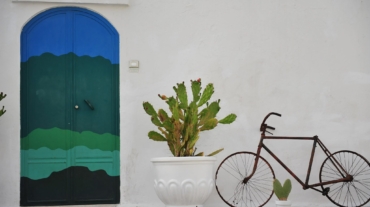 Una bicicletta appoggiata al muro vicino una porta colorata